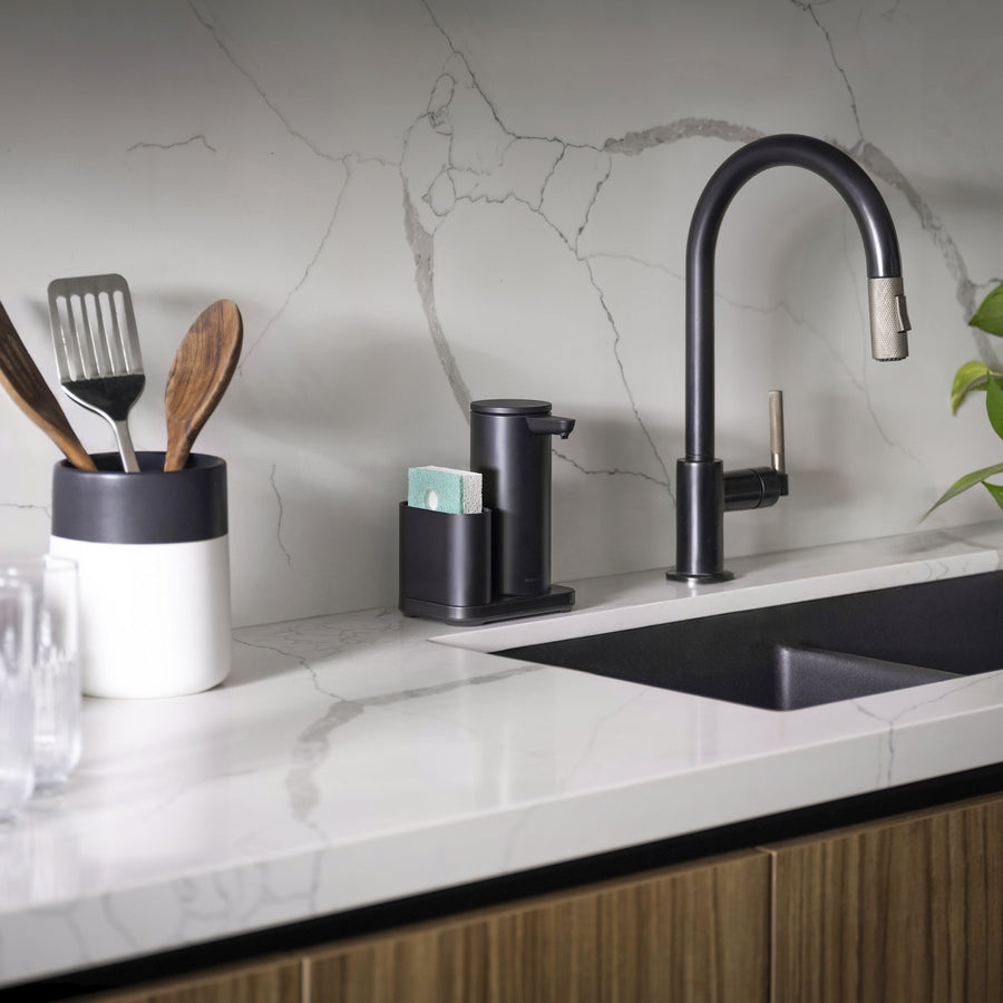 Lifestyle shot: Simplehuman Matte Black 9 oz Sensor Pump with Caddy next to modern black faucet, organized touch-free dispensing.